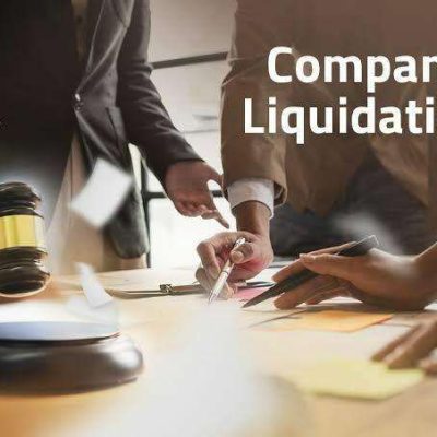 Business professionals reviewing documents and signing papers during a company liquidation process with a judge’s gavel visible on the table.